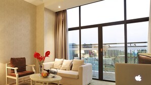 A modern living room with a white sofa, a brown armchair, a round coffee table, and a laptop on a glass table. - Gin Mao Yuan Hotel Shenzhen (Shenzhen)