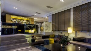 A modern living room with a sofa, coffee table, and a staircase leading to a bar area labeled "The Library Lounge". - Sardinero Madrid (Madrid)