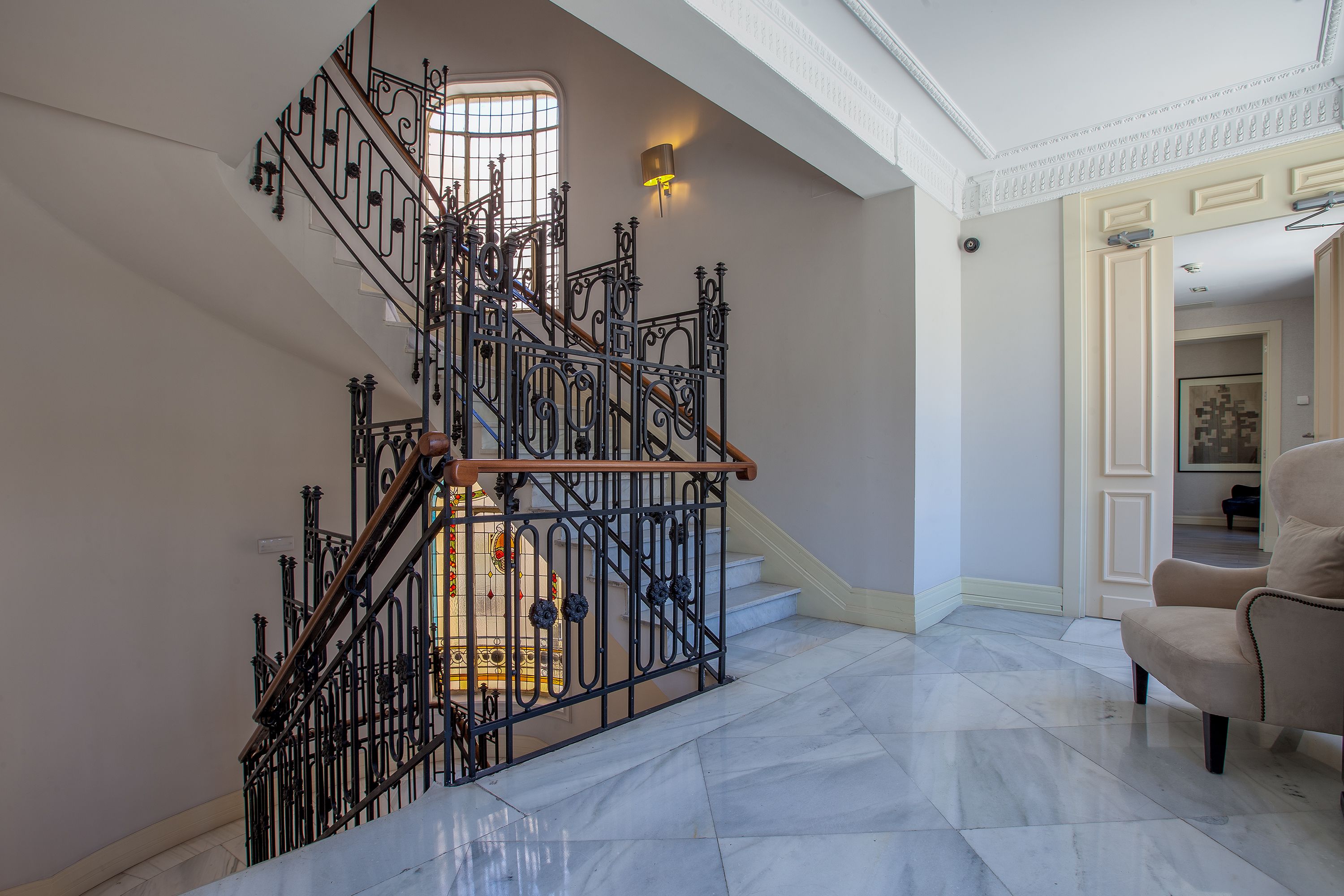 A grand staircase with ornate metal railings and a marble floor.