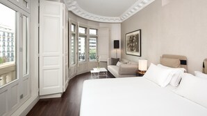 Una habitación de hotel con una cama grande, un sofá, una mesita de centro y una ventana con vistas a la ciudad.