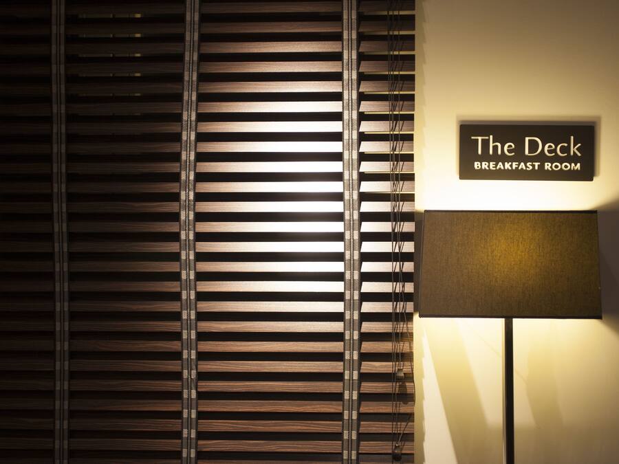 A sign for "The Deck Breakfast Room" with a lamp and blinds.