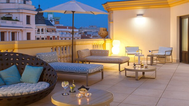 Una terraza en la azotea con mobiliario exterior, una mesa y una lámpara.