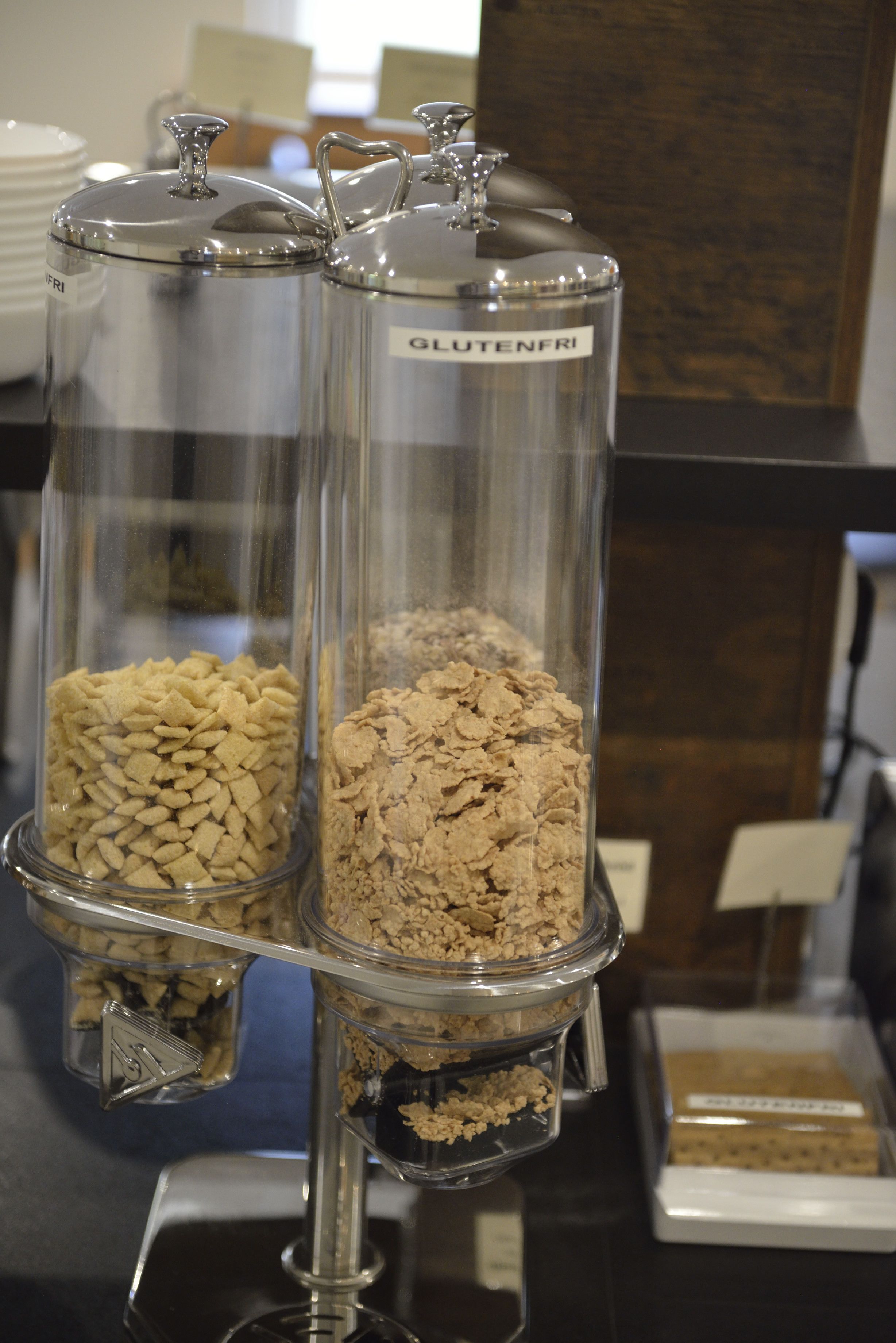 A food display with two containers labeled "GLUTENFRI" containing different types of cereal.