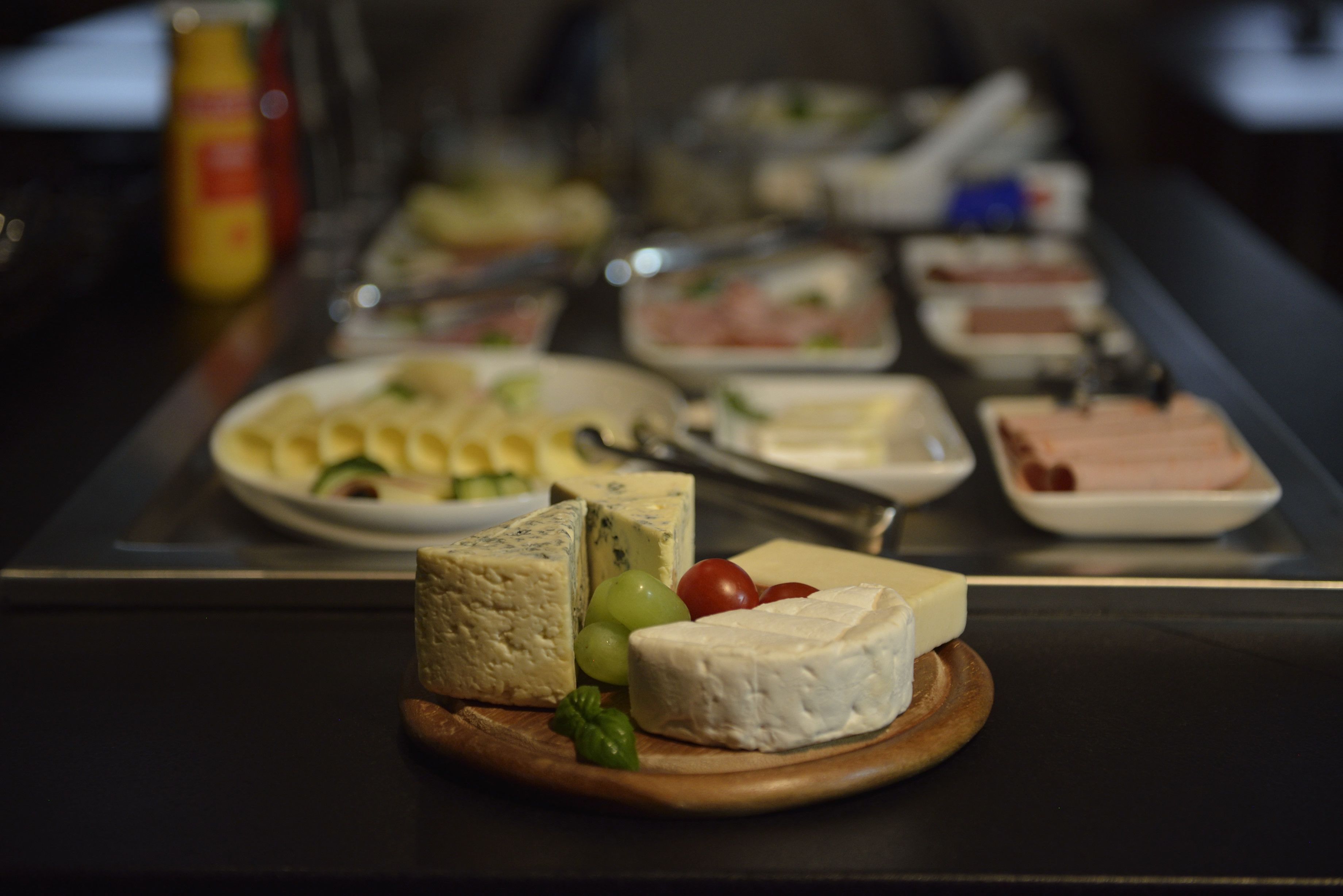 A buffet with various cheeses, fruits, and meats.