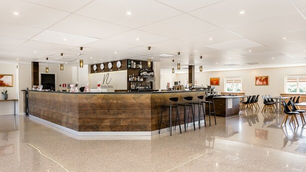 A modern hotel lobby with a central bar area, seating arrangements, and a reception desk. - Hotell Nova (Karlstad)