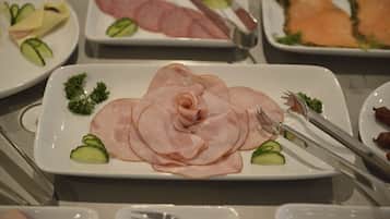 A buffet with various food items including sliced ham, smoked salmon, and vegetables.