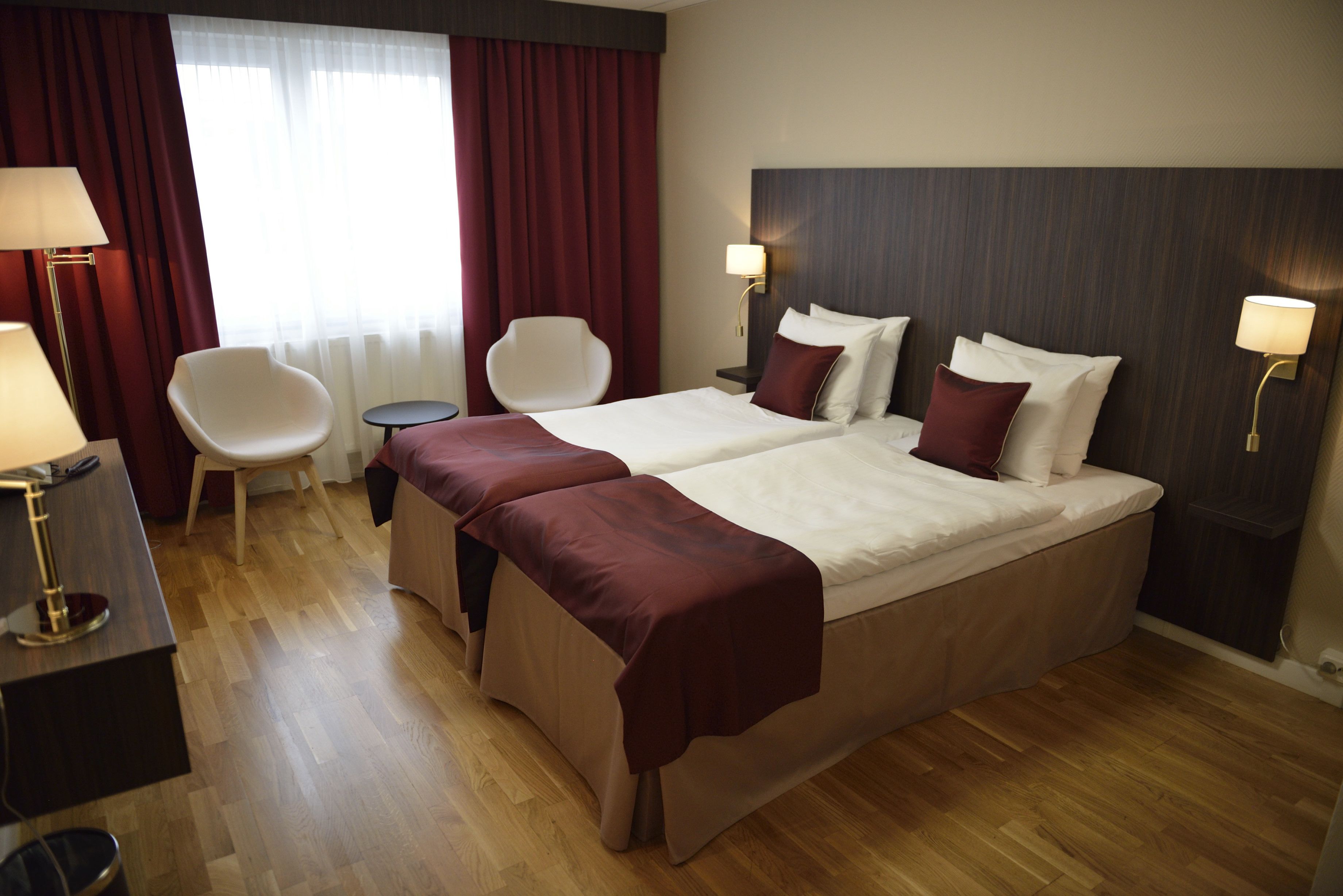 Ett hotellrum med en stor säng, två sängbord, en stol, ett skrivbord och en lampa.