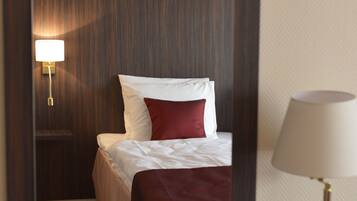 A hotel room with a bed, a nightstand with a lamp, and a mirror on the wall.