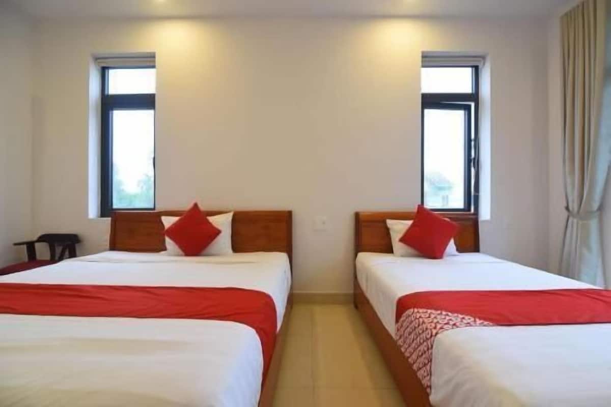 Una habitación de hotel con dos camas, cada una con un almohadón y una manta rojos.