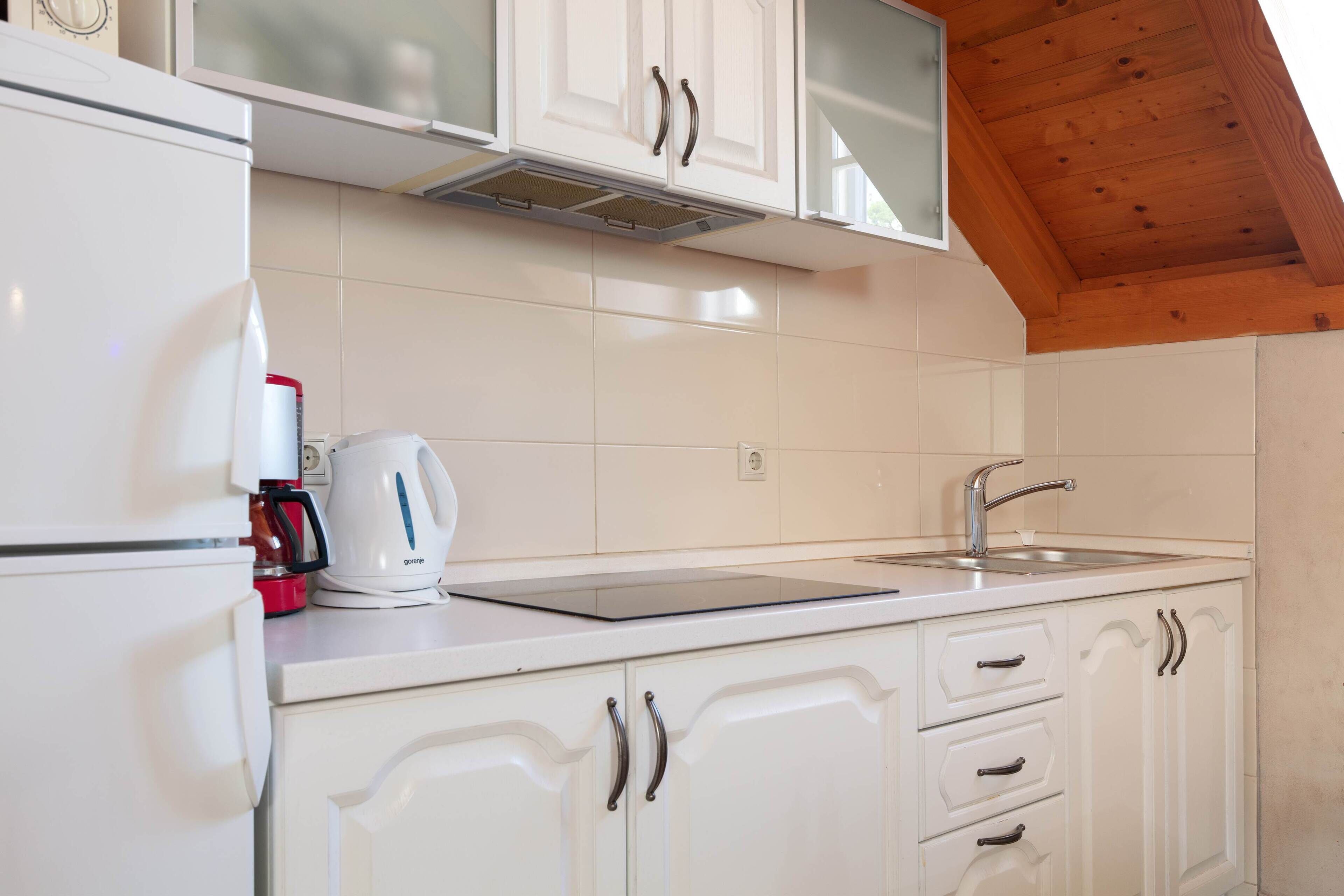A kitchen with white cabinets, a stainless steel sink, and a coffee maker.