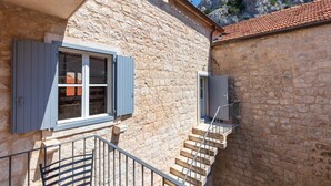 A stone building with a staircase leading to an upper level. - Vila Mama (Omis)