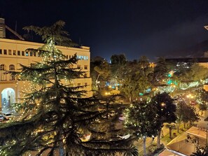 Un immeuble doté de nombreuses fenêtres et de balcons, entouré d’arbres et éclairé par des lampadaires.