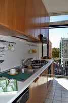A modern kitchen with wooden cabinets, stainless steel appliances, and a view of the city through large windows.