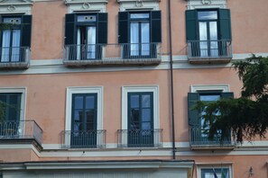 Un immeuble à plusieurs étages doté de balcons, de fenêtres avec volets et d’un style architectural classique.