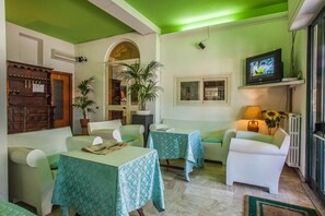 Un salon chaleureux avec des murs verts, des meubles blancs, un téléviseur et une cheminée.