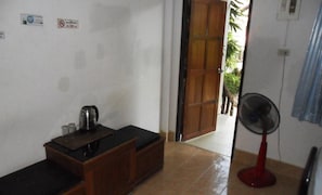 A small room with a wooden cabinet, a kettle, and a fan. - Aonang SR Bungalow (Krabi)