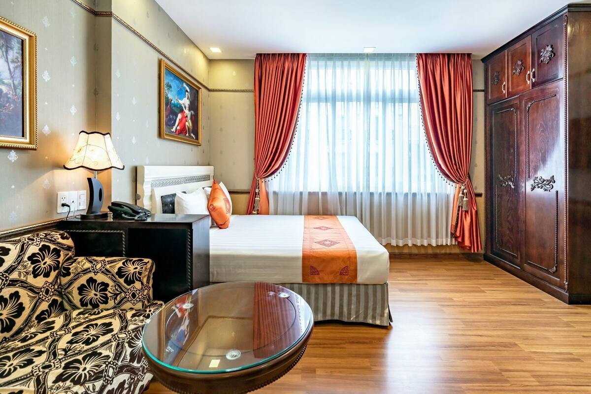 Hotelkamer met een bed, bureau, stoel, bank, glazen bijzettafeltje en een garderobe.