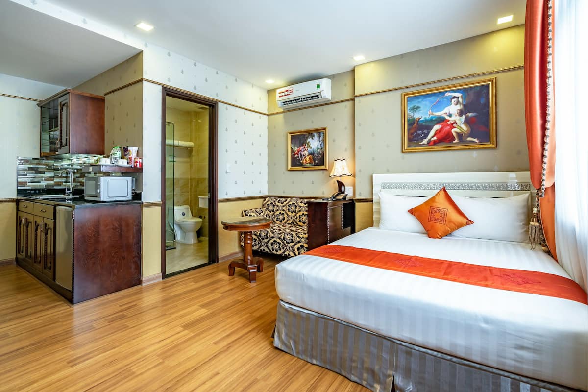 Een hotelkamer met een bed, een bureau, een stoel, een kleine tafel, een magnetron, een wastafel en een airconditioner.