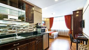 A modern kitchen with a built-in microwave, a sink, and a refrigerator. There is a dining area with a table and chairs, and a large window with curtains. - Collection O Emerald Luxury Apartment - Near SECC (Ho Chi Minh City)