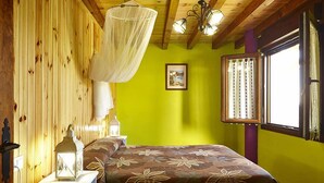 A room with a bed, a nightstand, a lamp, a picture on the wall, and a window with curtains. - Agroturismo Kasa Barri (Bermeo)