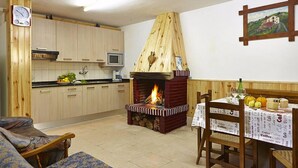 A cozy kitchen with wooden cabinets, a built-in microwave, and a wood-burning stove. - Agroturismo Kasa Barri (Bermeo)