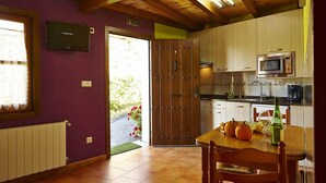 A kitchen with wooden cabinets, a microwave, and a dining table with chairs. - Agroturismo Kasa Barri (Bermeo)