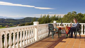 A terrace with a white balustrade, a table with a tablecloth, and a person seated at the table. - Agroturismo Kasa Barri (Bermeo)