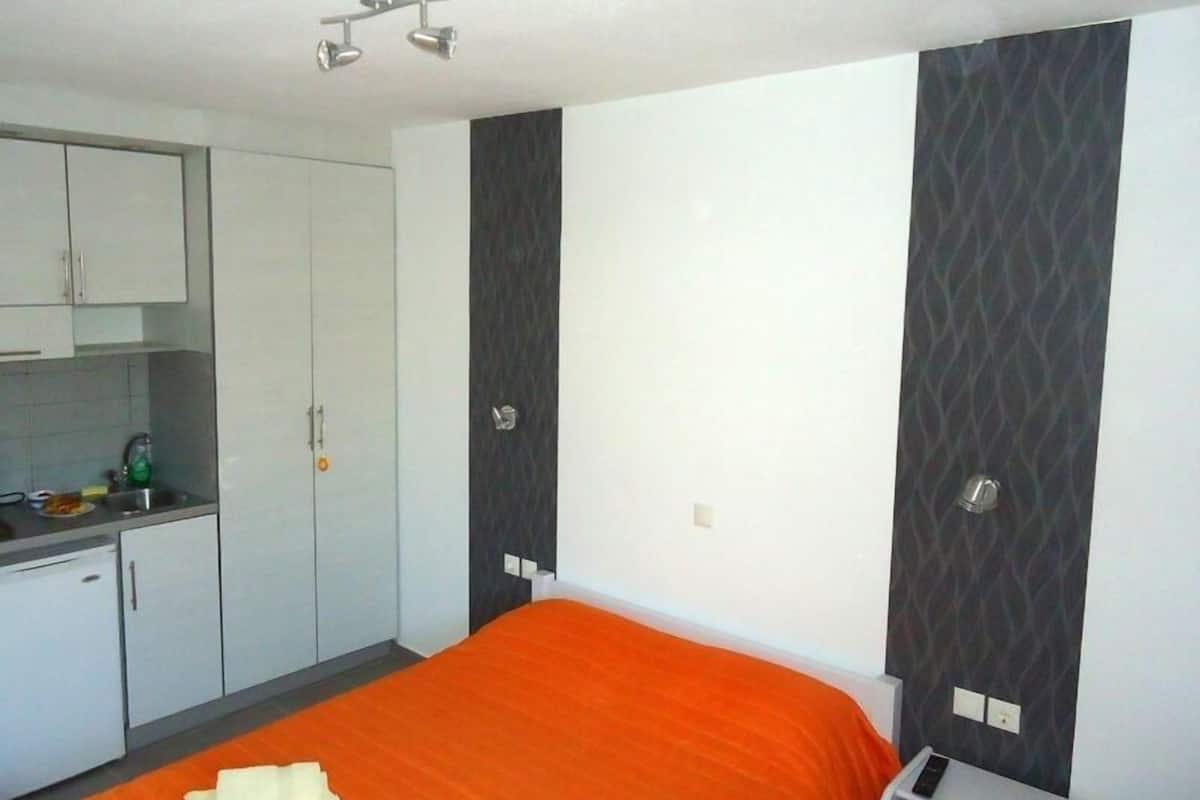 Une chambre d’hôtel avec un lit, une petite kitchenette et une armoire.