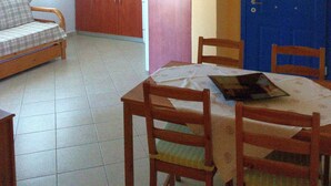 A compact living space with a kitchenette, a dining area with a table and chairs, and a sofa.
