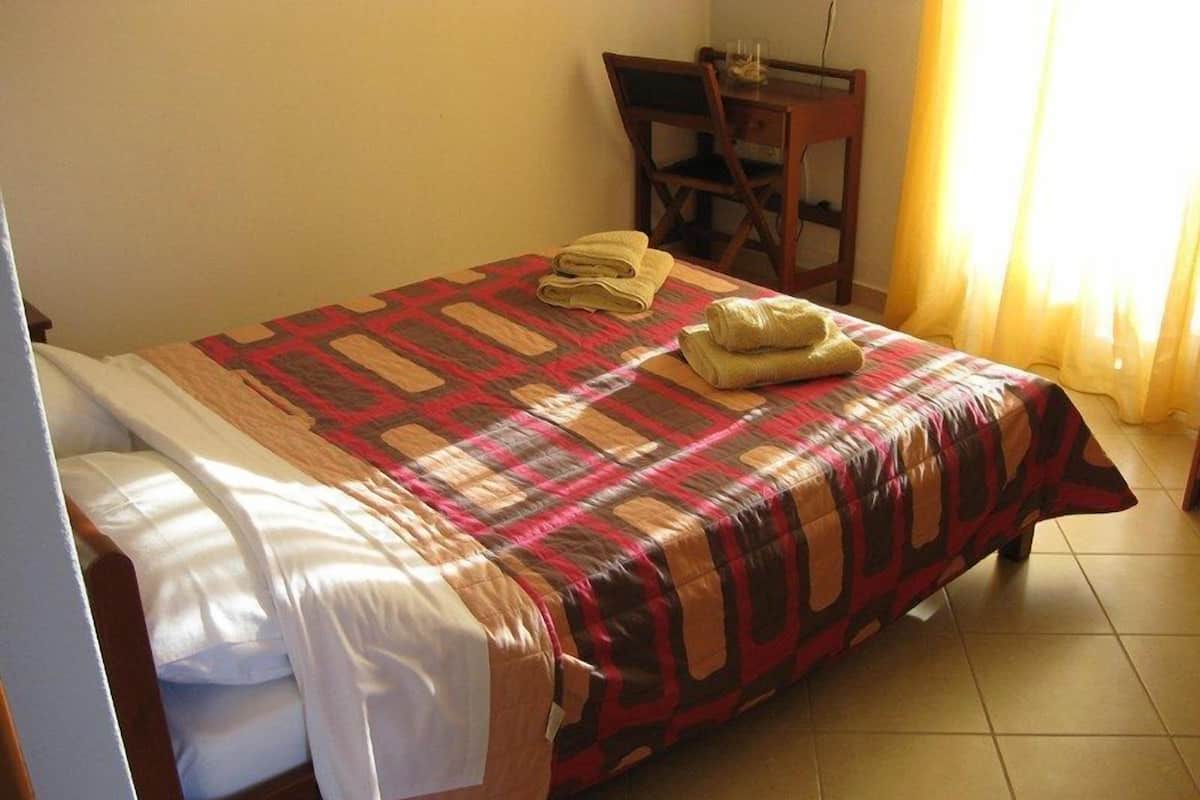 Un lit bien fait, avec une couvre-lit à motifs et deux serviettes pliées.