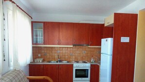 A compact kitchen with wooden cabinets, a white stove, and a refrigerator.