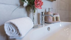 A bathroom with a white sink, a rolled white towel, and a vase with flowers. - La Residenza sul Largo (Cagliari)