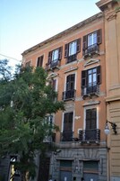 Un edificio de varios pisos con balcones y persianas, que presenta un estilo arquitectónico clásico.