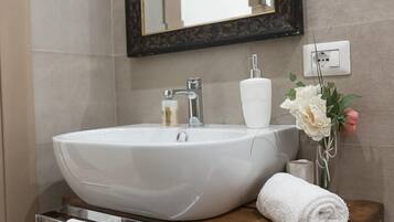 Une salle de bain avec un grand lavabo ovale, un miroir à cadre foncé et un meuble-lavabo en bois.