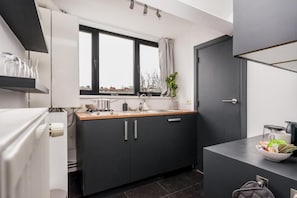 A compact kitchen with a window, a sink, and a countertop. - Simone's Kitchen B&B (Antwerp)