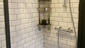 A corner shower with a handheld showerhead and a handheld faucet.