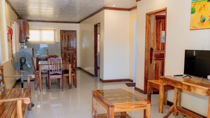 A spacious living area with wooden furniture, a glass-top coffee table, and a television on a wooden stand. - Villa Paraiso Resort and Waterpark Camiguin (Mambajao)