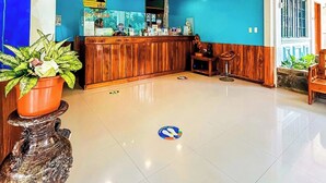 A reception area with a wooden counter, a blue wall, and a tiled floor. - Villa Paraiso Resort and Waterpark Camiguin (Mambajao)