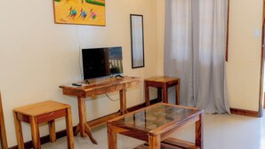A living room with a wooden TV stand, a glass-top coffee table, and two matching wooden side tables. - Villa Paraiso Resort and Waterpark Camiguin (Mambajao)