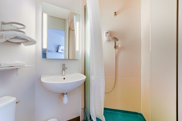 Un baño con lavamanos, espejo y ducha blancos.