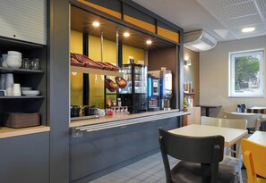A cafe with a counter, seating area, and a window.
