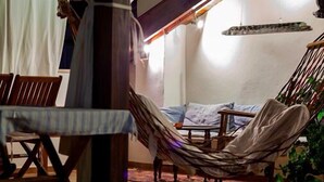 A hammock chair, a wooden table, and a bed with pillows in a room with a wooden ceiling and a hanging light fixture. - Turk Evi (Kas)