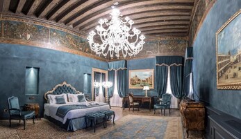 Una camera da letto lussuosa con un letto grande, un lampadario elaborato e arredamento classico.