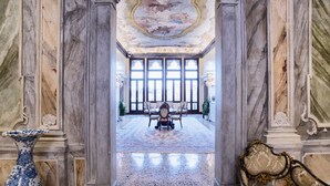 A grand hallway with marble columns, a large ornate ceiling, and a dining area with a chandelier.