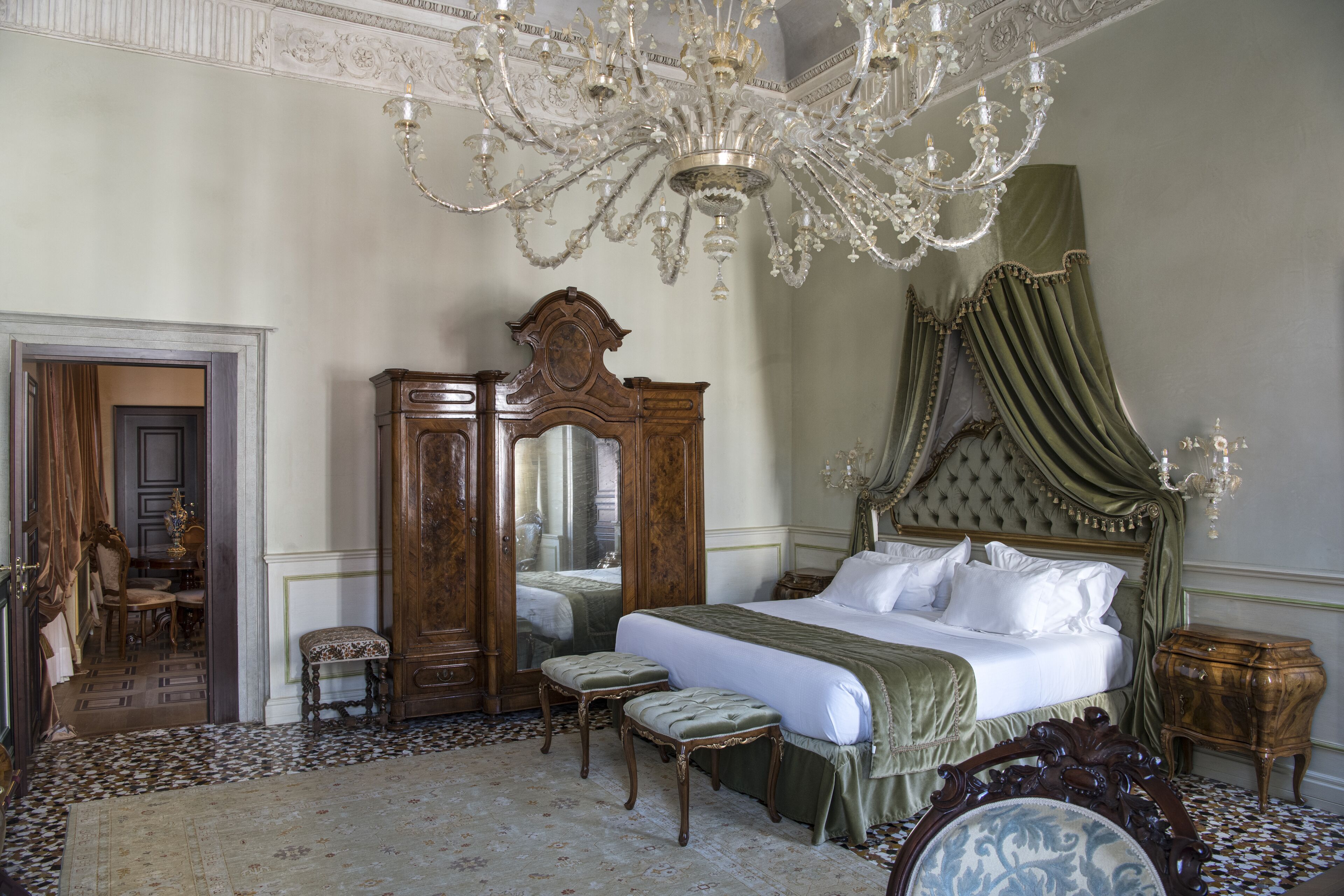 Une chambre à coucher classique, avec un grand lit, des meubles richement décorés et un lustre.