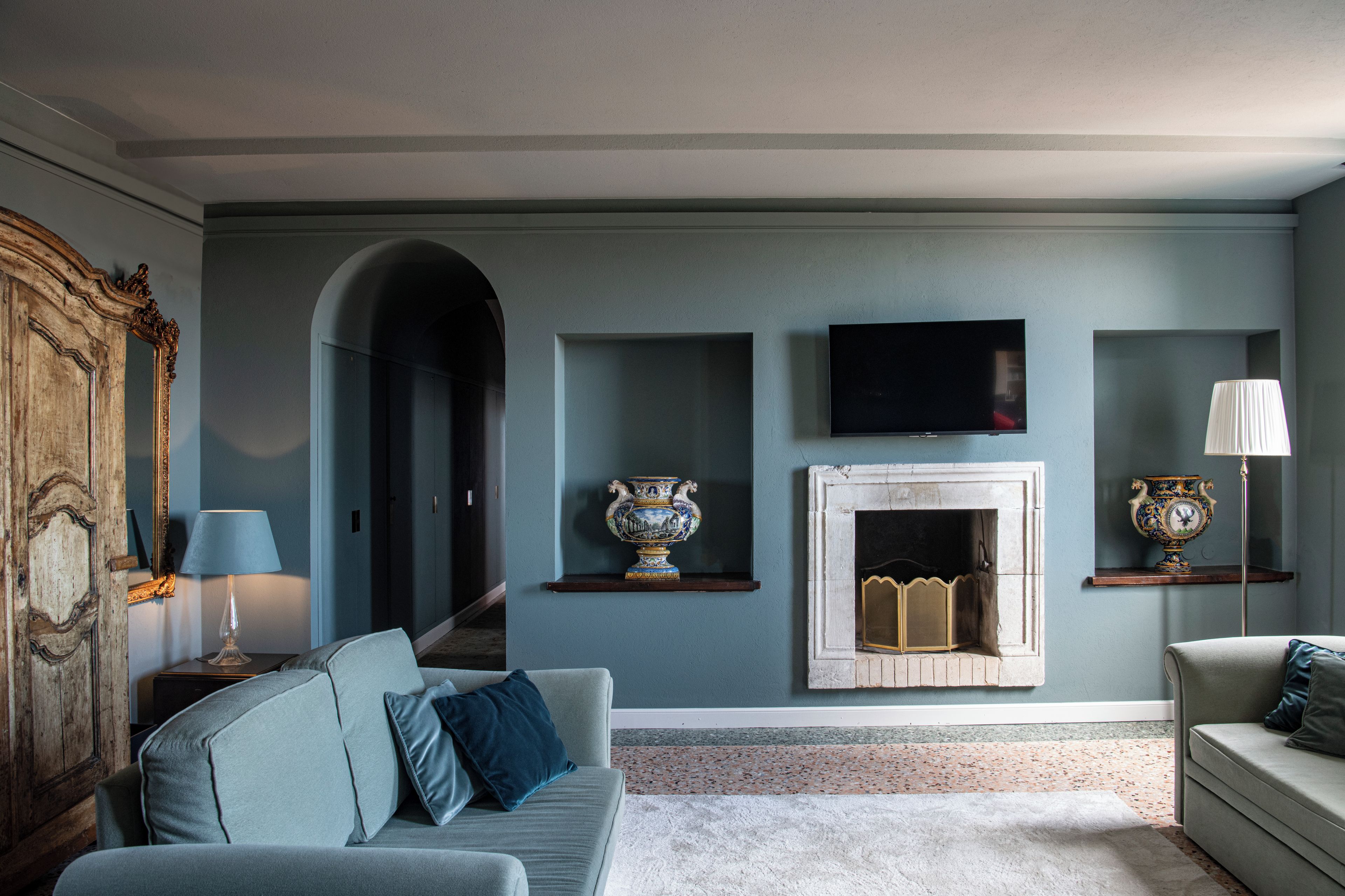 A living room with a sofa, a television, a fireplace, and decorative vases.
