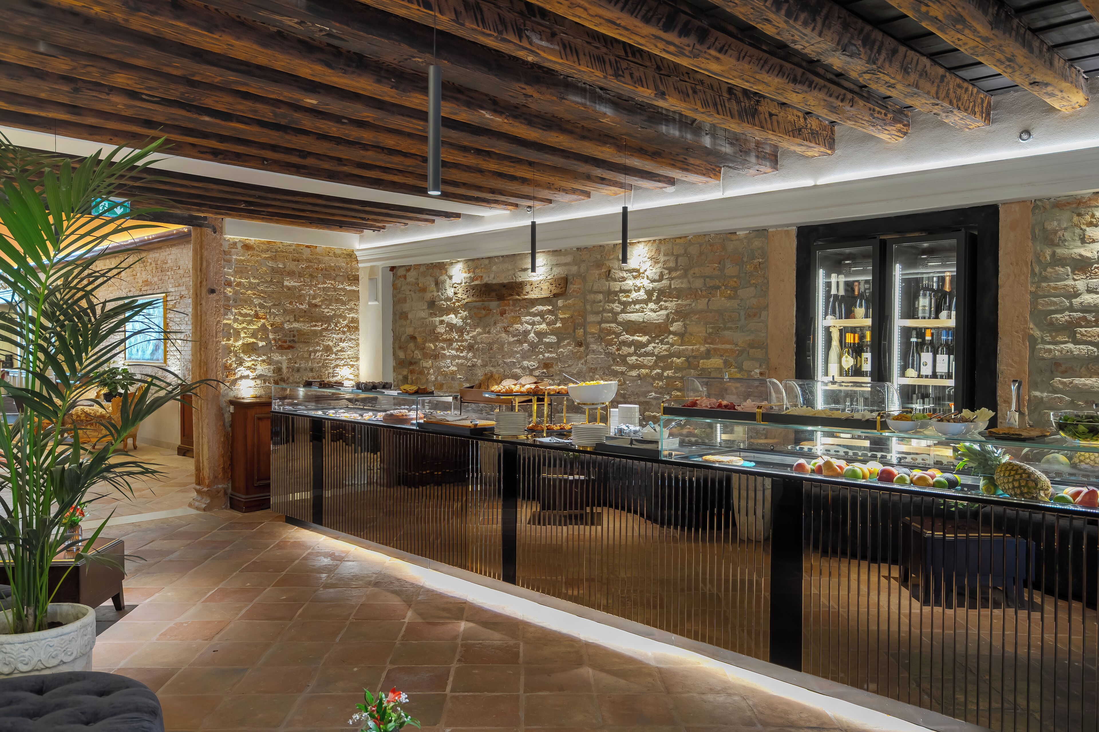 Un'area buffet con pareti in pietra, una vetrina in vetro che espone cibi e un soffitto in legno.