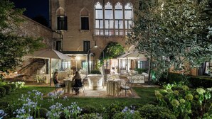A courtyard with outdoor seating, a fountain, and a brick building with large windows.