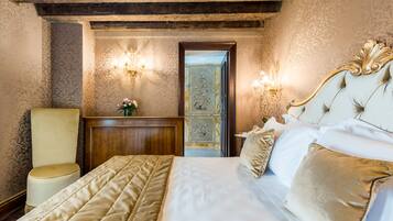 Quarto com uma cama grande, cabeceira de madeira, mesa de cabeceira e duas arandelas na parede.