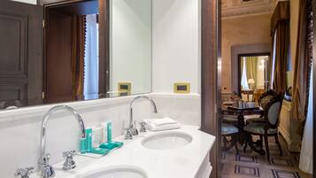 A bathroom with two sinks, a large mirror, and a dining area with a table and chairs.